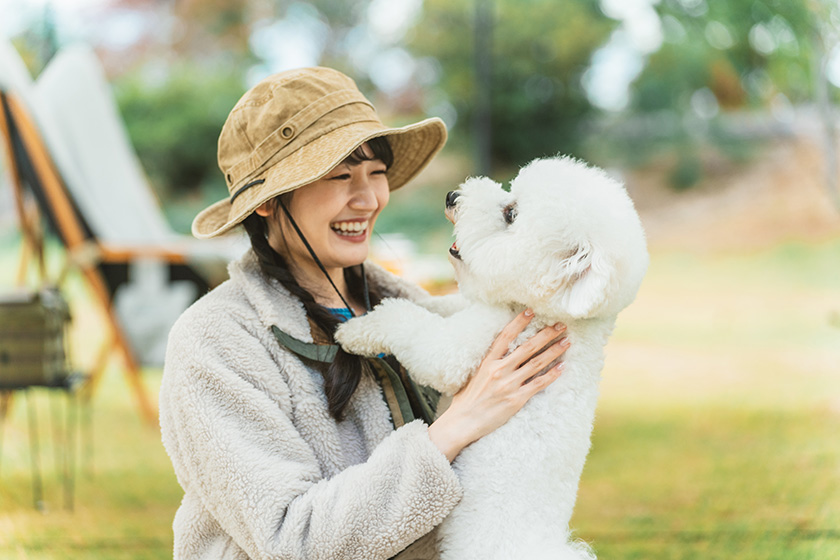 自然を感じられるレジャー施設で愛犬と遊ぶ女性